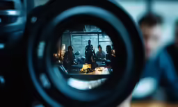a camera being used by people with a reflection on a mirror