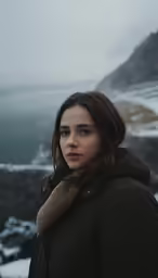 a young woman posing for a photo by a mountain lake