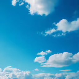 the view of a group of people in a blue shirt standing under a bright cloud filled sky