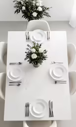 a white table set for six with place settings and flowers