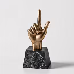 a gold sculpture that has a rock and roll hand on it