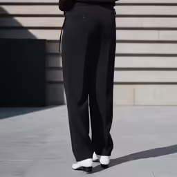 a woman wearing black pants standing in front of a building