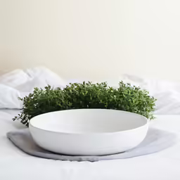 a white bowl that is on a bed