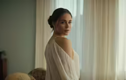 a girl in a dress posing by a window