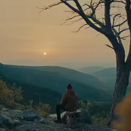 the person is sitting on top of the hill alone