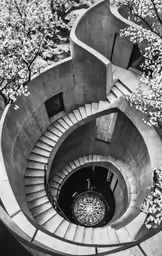 this black and white photo shows the staircase and a spiral - like opening between the buildings