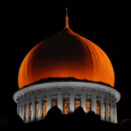 an orange dome stands at night as it rises above the silhouette of the buildings