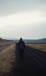 a lone man walking down the middle of a road