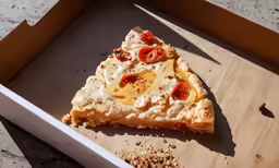 half of pizza with toppings sitting on top of a piece of cardboard