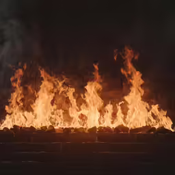 a fire filled brick wall with fire tongues blazing in the air