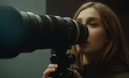 a woman looking through a camera lens