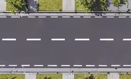 a lone car traveling down a road on a city street