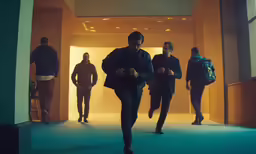 the men are walking down the hall towards the camera