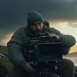 a man sitting in front of a camera holding a small device