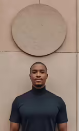 the black man wearing the black turtleneck in front of an artistic circle