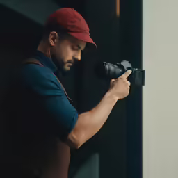 a man with a red cap is using an electric flash light