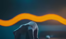 a hand holding a cell phone in front of a bright orange light
