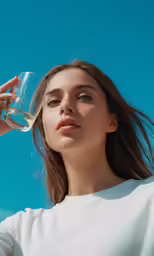 a woman is holding a wine glass and staring into the sky