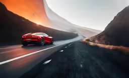 a red sports car driving on a hilly road
