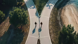 two people cross a winding road near the ocean