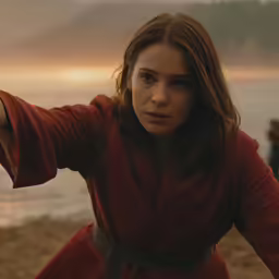 woman with long hair wearing a red robe near the beach