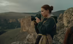 a woman taking a picture in the mountains