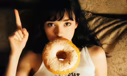 a woman wearing white tank top and eating a donut