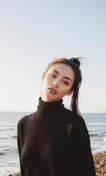 a woman standing by the water wearing black sweater and shorts