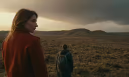 a couple of people walking across a field