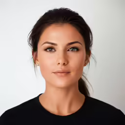 a woman looking at the camera in front of a white wall