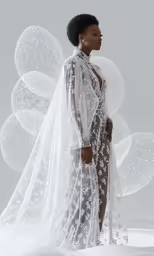 a woman in a white lingerie stands in front of an intricately - designed floral backdrop