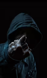 a hooded man wearing a black jacket, holding a cigarette