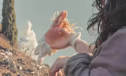 woman with hands extended out reaching for something near a mountain