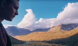woman looking out at mountains with trees and road