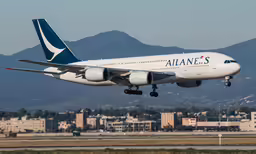 an airplane flying above the ground and some buildings