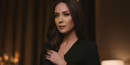 a woman wearing black clothing stands next to a lamp