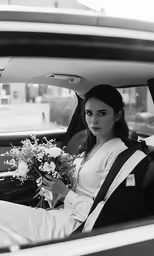 a woman sitting in the passenger seat of a car holding flowers