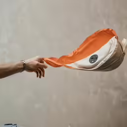 a man holding a flag on top of a white wall