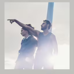 two men standing next to each other pointing at the sky