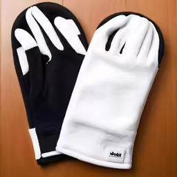 a pair of black and white gloves sitting on top of a wooden floor