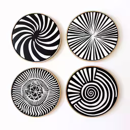 four black and white ceramic plates on a wall,the plates have a circular design in different shapes