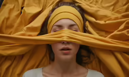 a woman wrapped in gold cloth covering her face with the drapers pulled over her