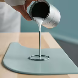 someone pouring milk from a mug into a metal container