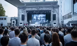 a crowd of people standing around on stage with a projected image