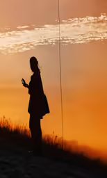 a girl on the field at sunset taking a picture