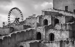 a ferris wheel next to an ancient stone building