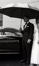 the bride and groom are standing in front of their car while holding an umbrella