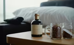 a glass and bottle on the end of a small table