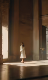 a woman standing near tall building pillars in the sun