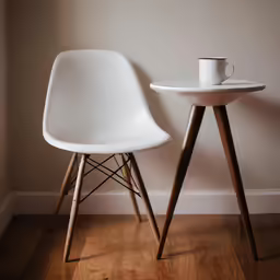 a white chair and a white table sit against the wall